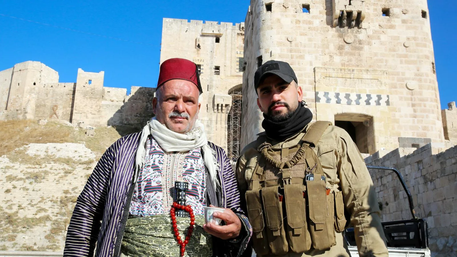 Сириец рядом с боевиком «Хайят Тахрир аш-Шам»*, 1 декабря 2024 года. Juma Mohammad