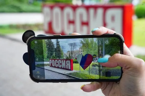 Девушка фотографирует на телефон украшения города к майским праздникам в Донецке