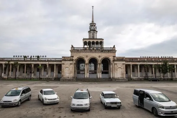 Машины у разрушенного вокзала города Сухума