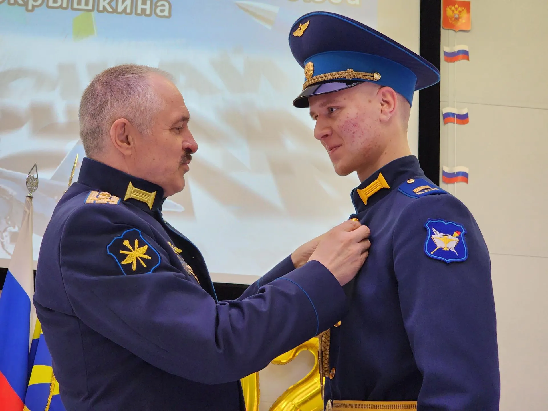 Директор летной школы Ярослав Долинчук вручает Леониду Бабаю серебряный значок самолета. Фото: REGIONS/Наталья Дорошева