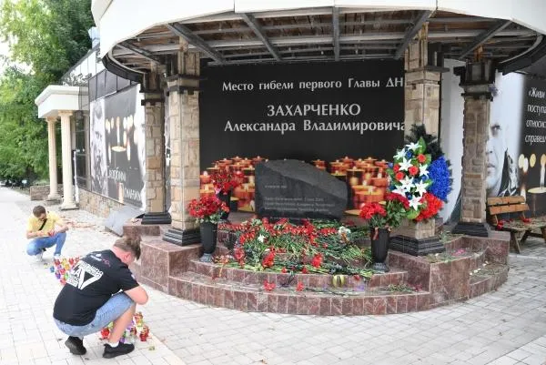 Мужчины зажигают свечи по случаю годовщины гибели первого главы ДНР Александра Захарченко у мемориального знака возле кафе «Сепар» в Донецке