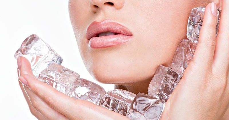 женщина протирает лицо кубиком льда